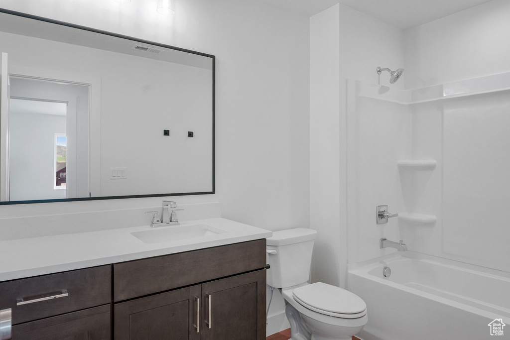 Full bathroom featuring vanity, washtub / shower combination, and toilet