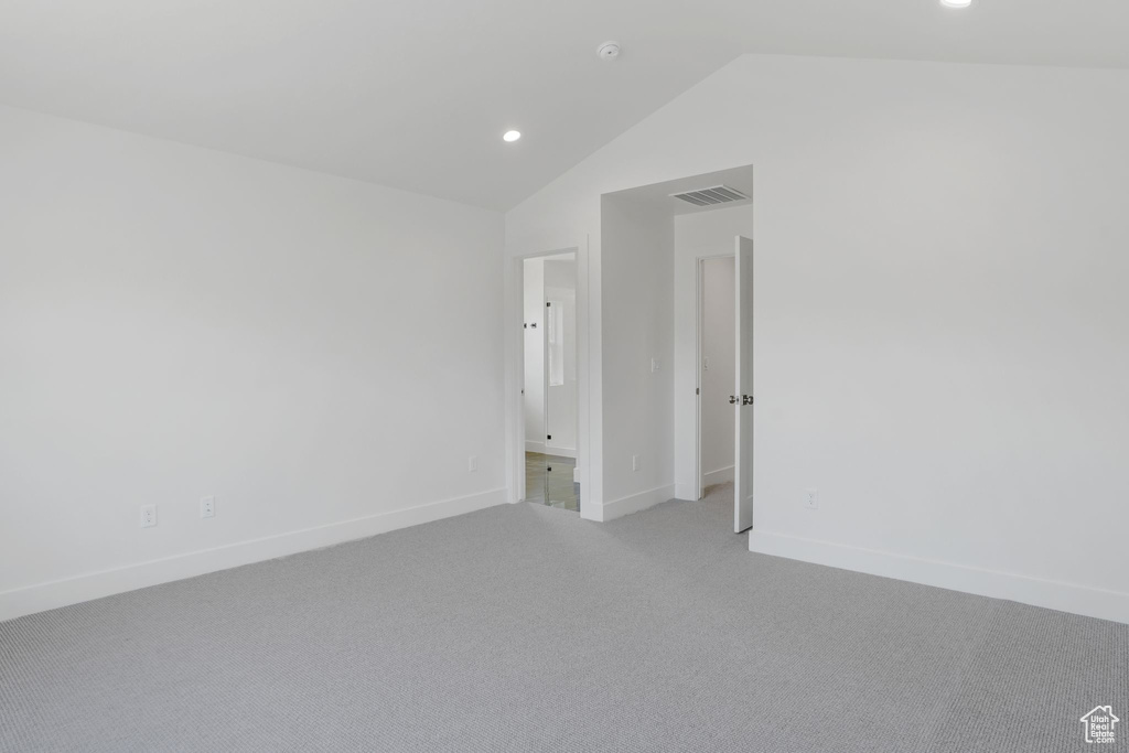 Carpeted spare room featuring lofted ceiling