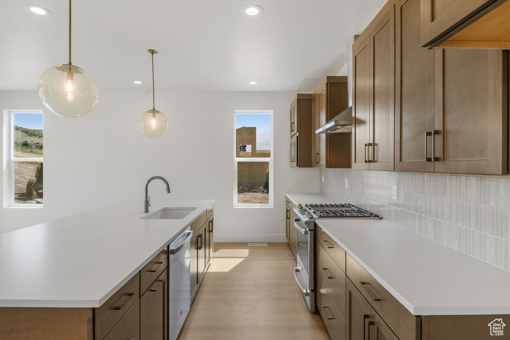 Kitchen featuring decorative backsplash, decorative light fixtures, appliances with stainless steel finishes, and a wealth of natural light