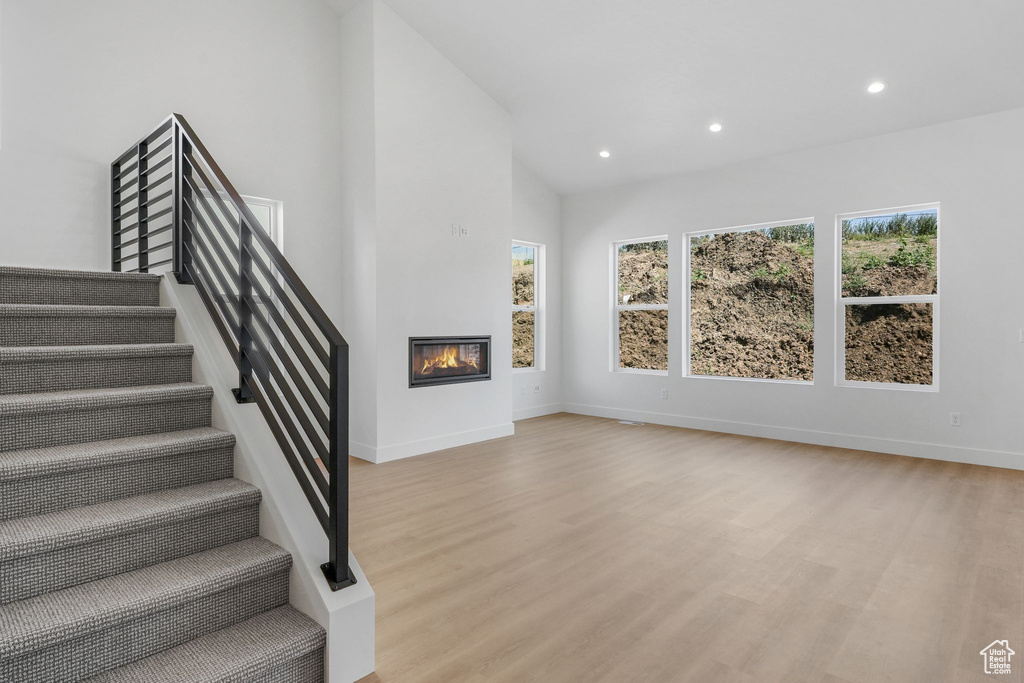 Stairway featuring light hardwood / wood-style floors and high vaulted ceiling