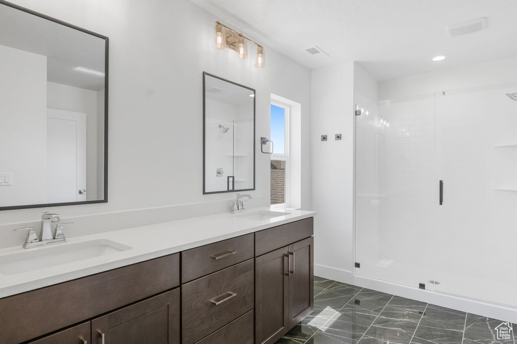 Bathroom with an enclosed shower, tile patterned flooring, and double sink vanity