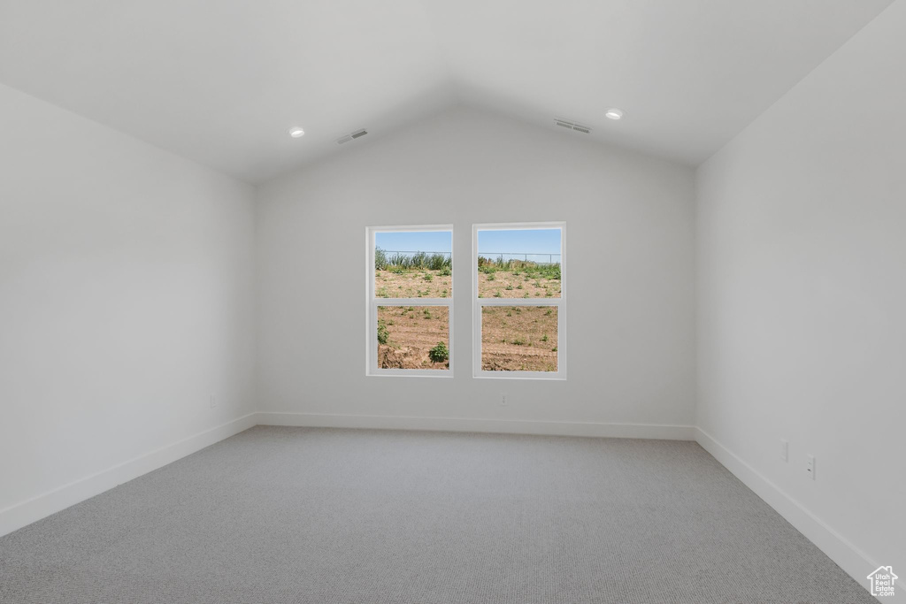 Spare room with carpet flooring and lofted ceiling