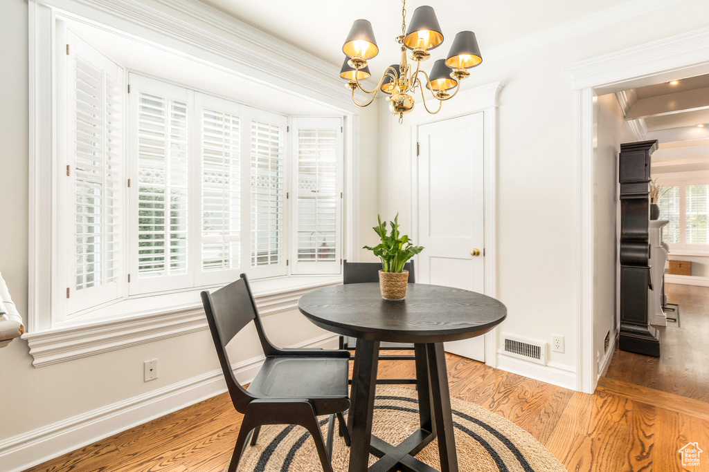 Dining area with light hardwood / wood-style floors, a chandelier, and ornamental molding