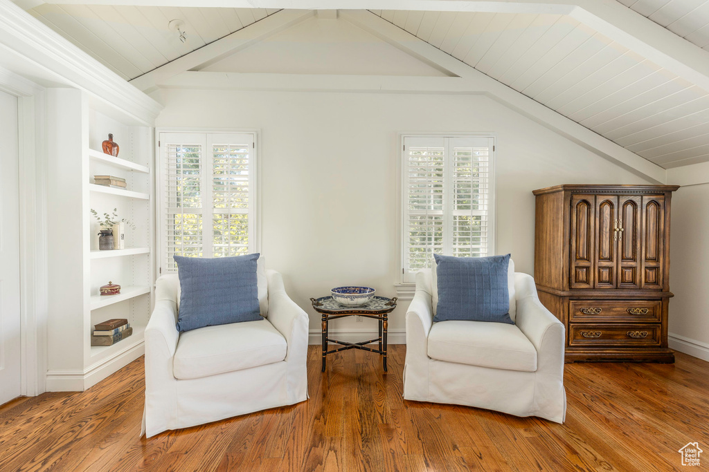 Sitting room featuring lofted ceiling, built in shelves, and wood-type flooring