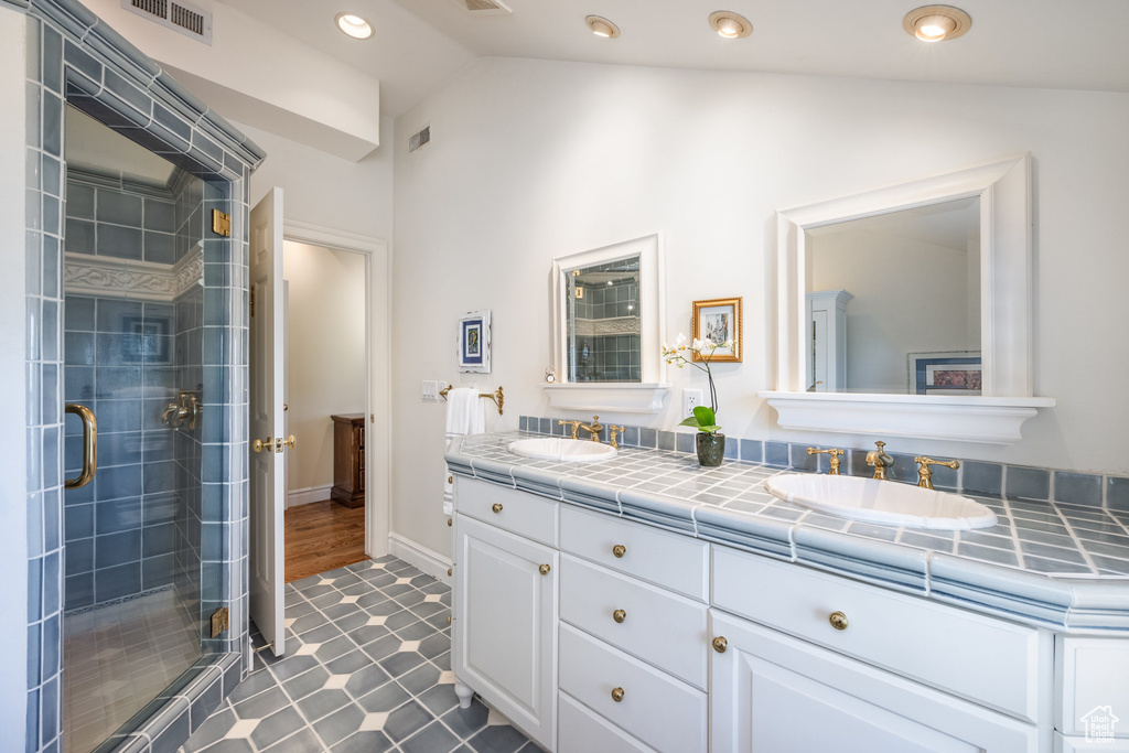 Bathroom with vaulted ceiling, hardwood / wood-style flooring, walk in shower, and vanity