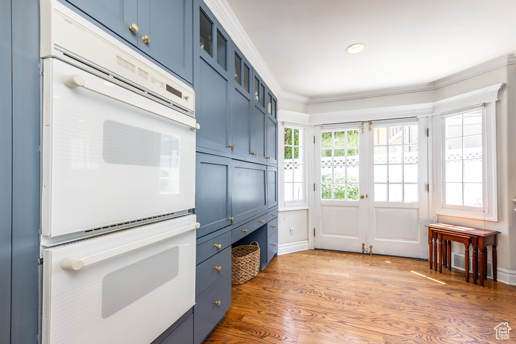 Kitchen with hardwood / wood-style flooring, white double oven, crown molding, and blue cabinetry