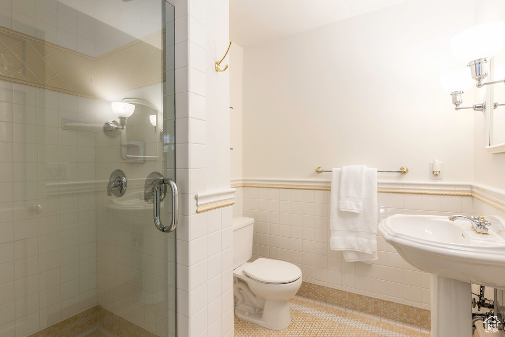 Bathroom with tile walls, toilet, walk in shower, and tile patterned flooring