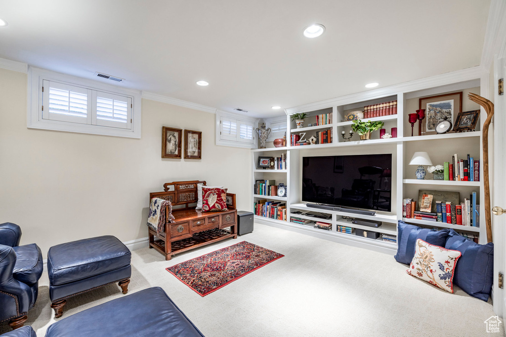 Living room with crown molding, light colored carpet, and built in shelves