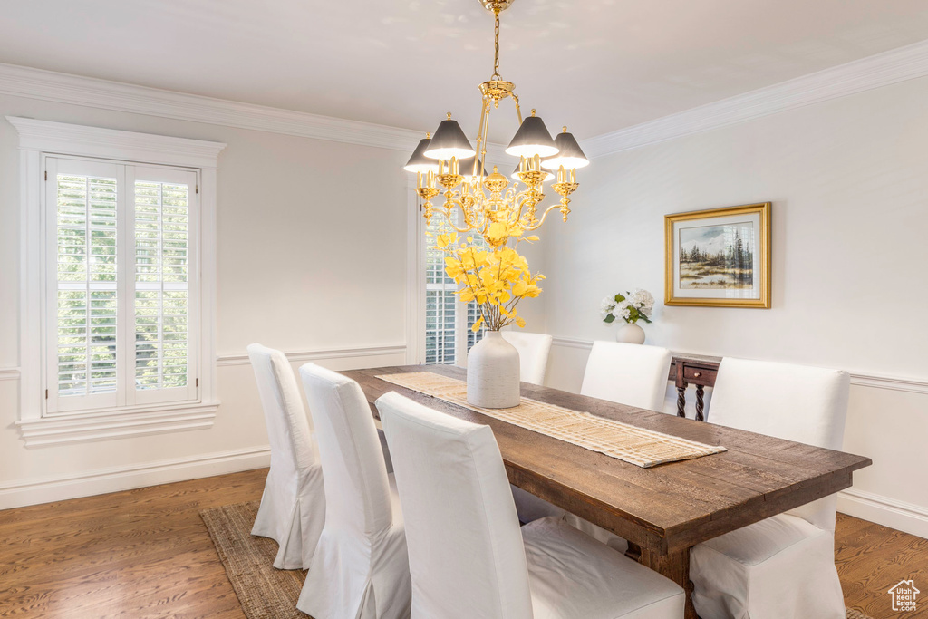 Dining area with crown molding, dark wood-type flooring, and a notable chandelier