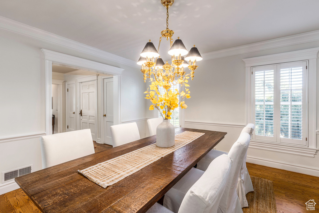 Dining space featuring ornamental molding, dark hardwood / wood-style flooring, and an inviting chandelier