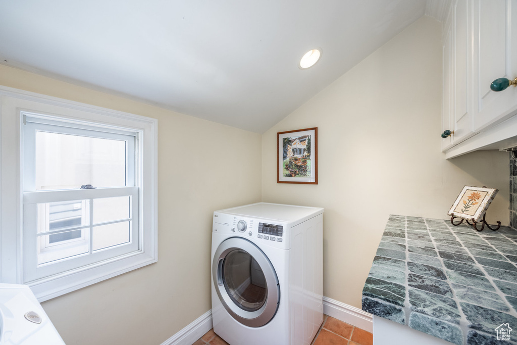 Washroom featuring light tile patterned flooring, cabinets, and washer / dryer