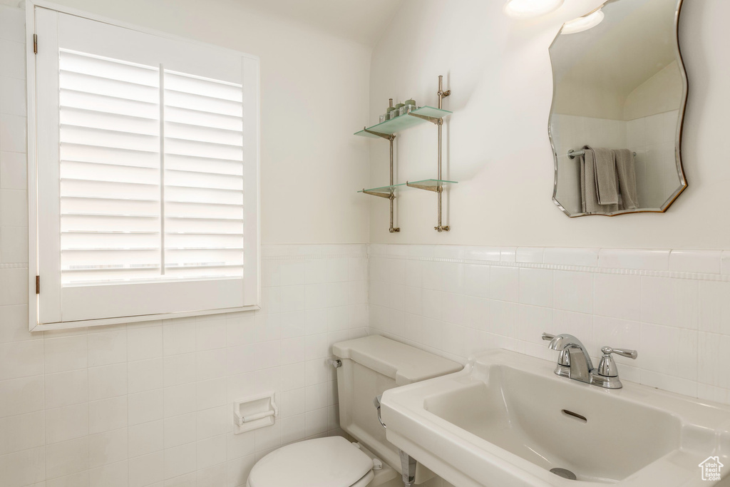 Bathroom featuring sink, tile walls, and toilet