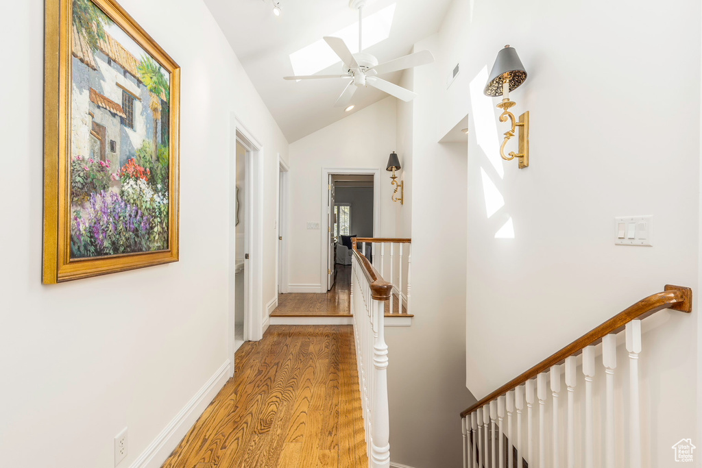 Hall featuring vaulted ceiling with skylight and hardwood / wood-style floors