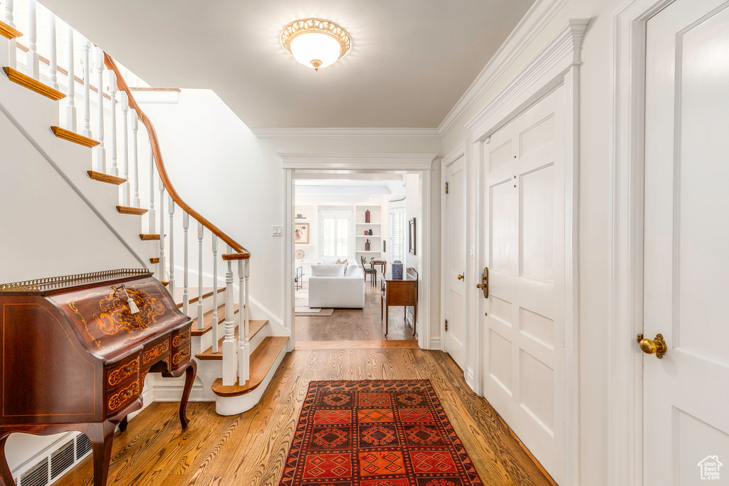 Entrance foyer featuring crown molding and light hardwood / wood-style floors