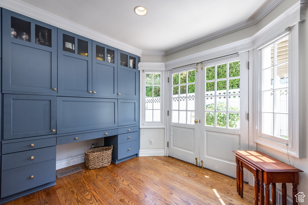 Interior space with plenty of natural light, hardwood / wood-style floors, built in desk, and ornamental molding