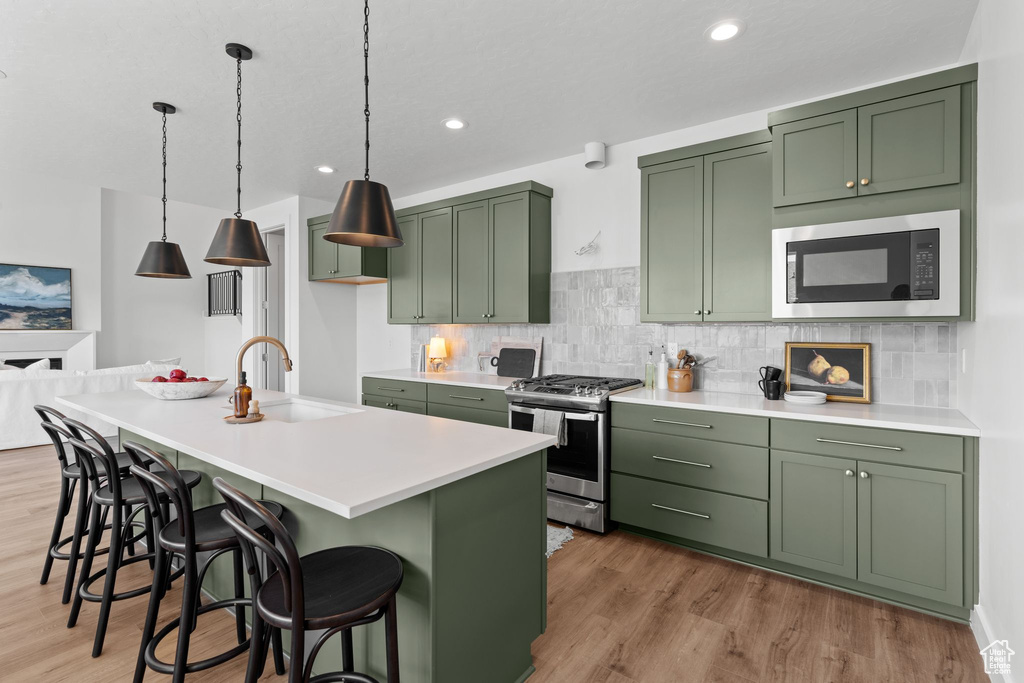 Kitchen with light hardwood / wood-style flooring, black microwave, sink, and stainless steel gas stove