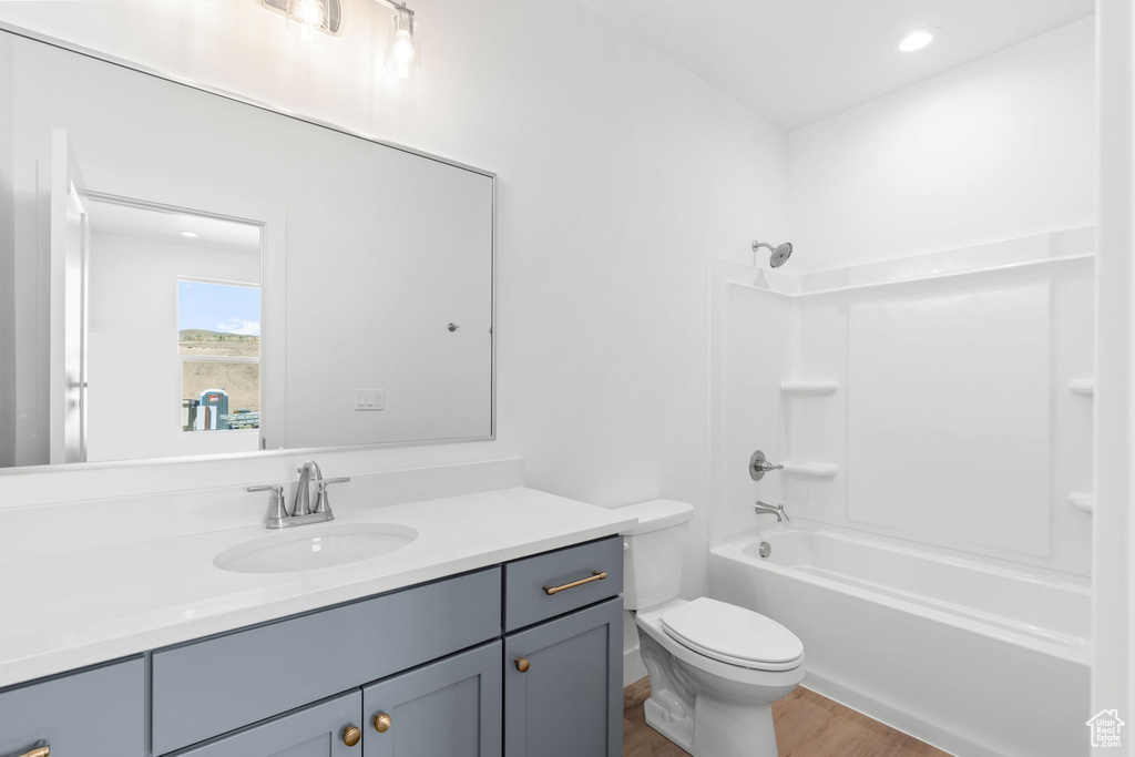 Full bathroom featuring hardwood / wood-style flooring, toilet, shower / tub combination, and vanity