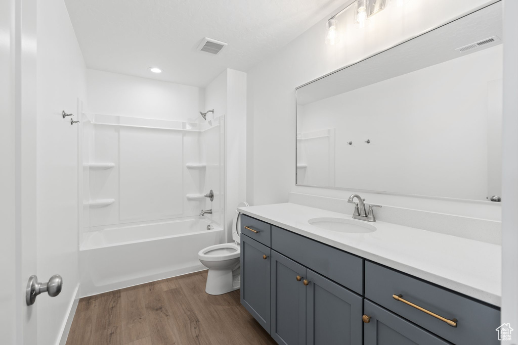 Full bathroom with bathtub / shower combination, wood-type flooring, toilet, and vanity