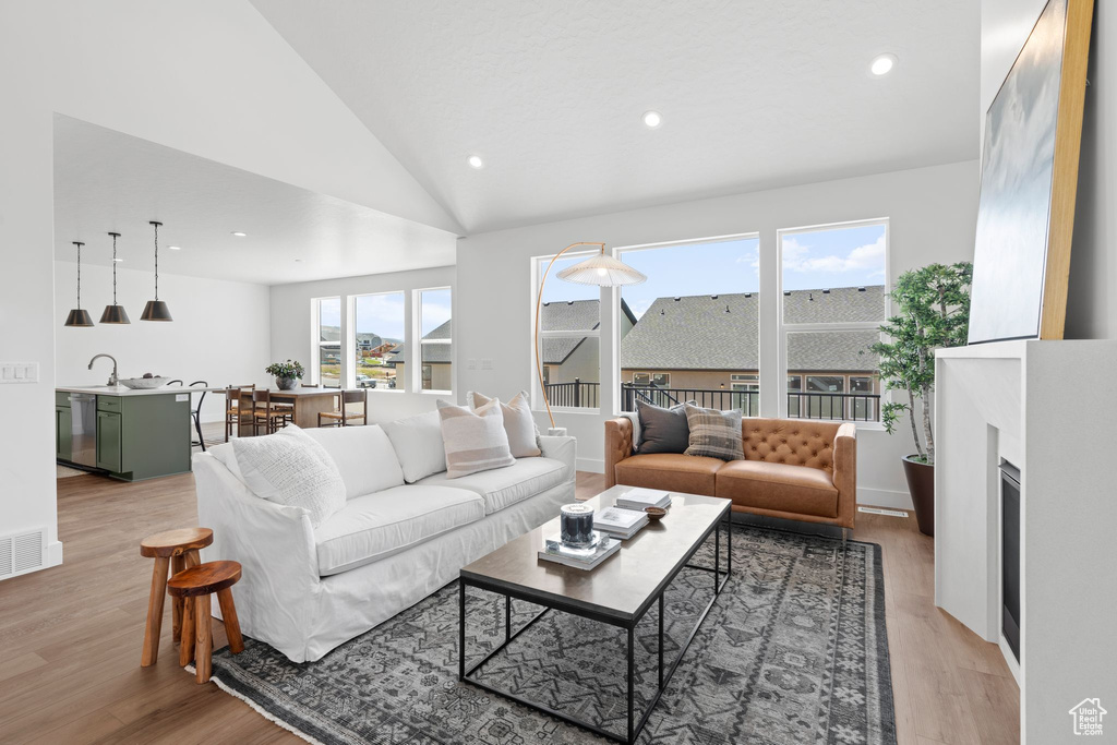 Living room featuring a wealth of natural light, light hardwood / wood-style flooring, high vaulted ceiling, and sink