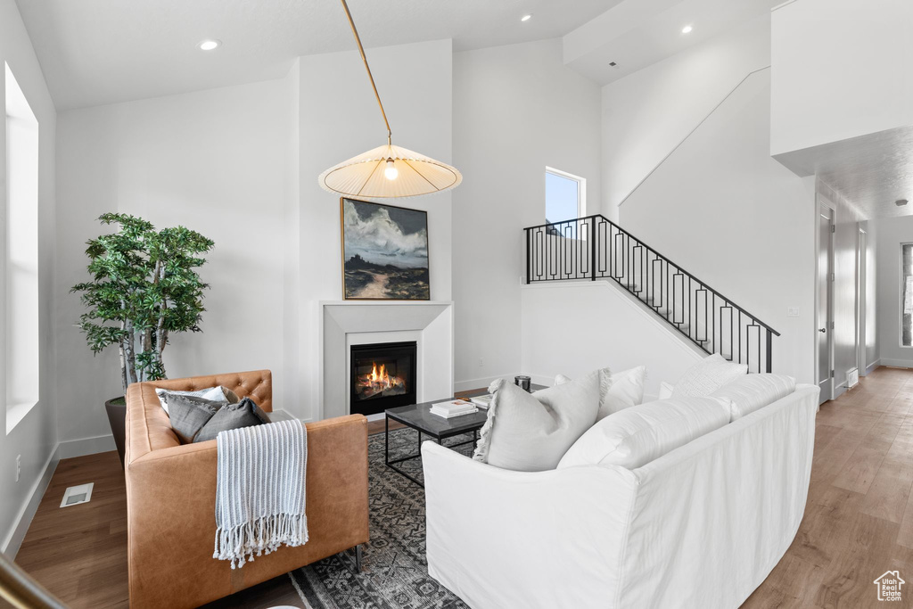 Living room with high vaulted ceiling and hardwood / wood-style floors