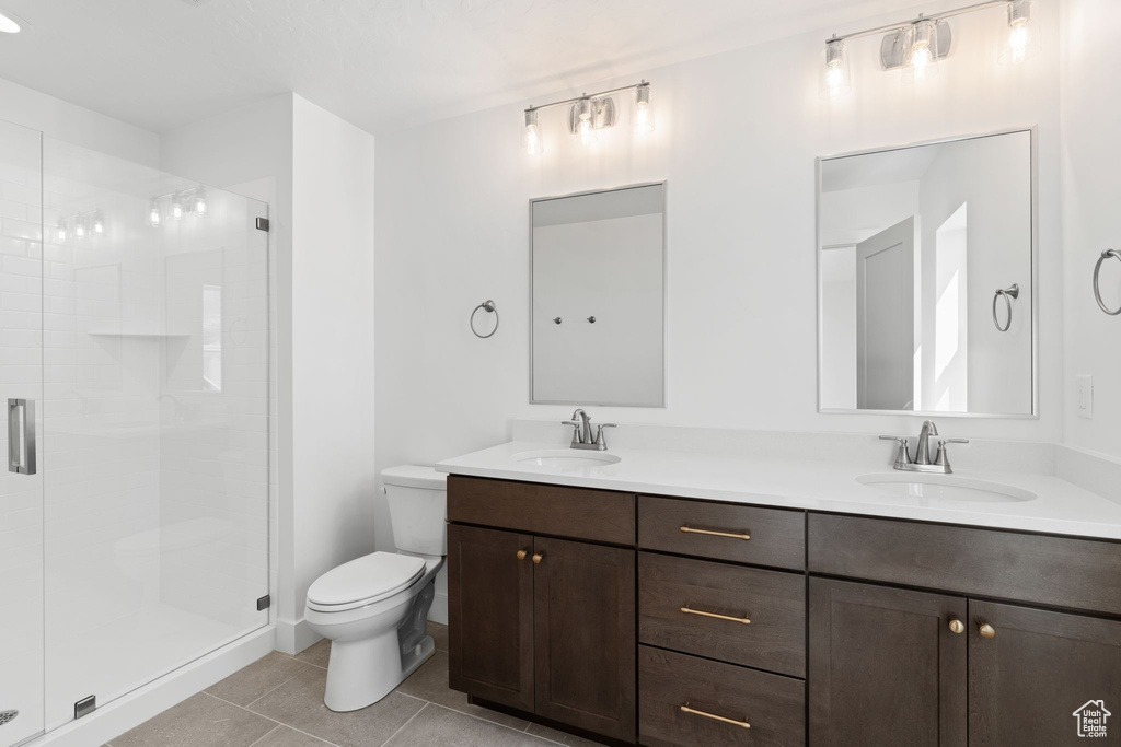 Bathroom with tile patterned floors, walk in shower, dual vanity, and toilet