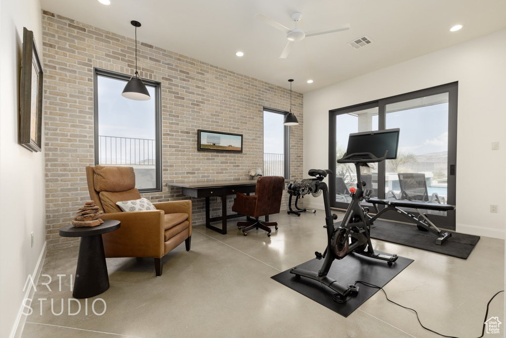 Workout room featuring a healthy amount of sunlight, brick wall, and ceiling fan