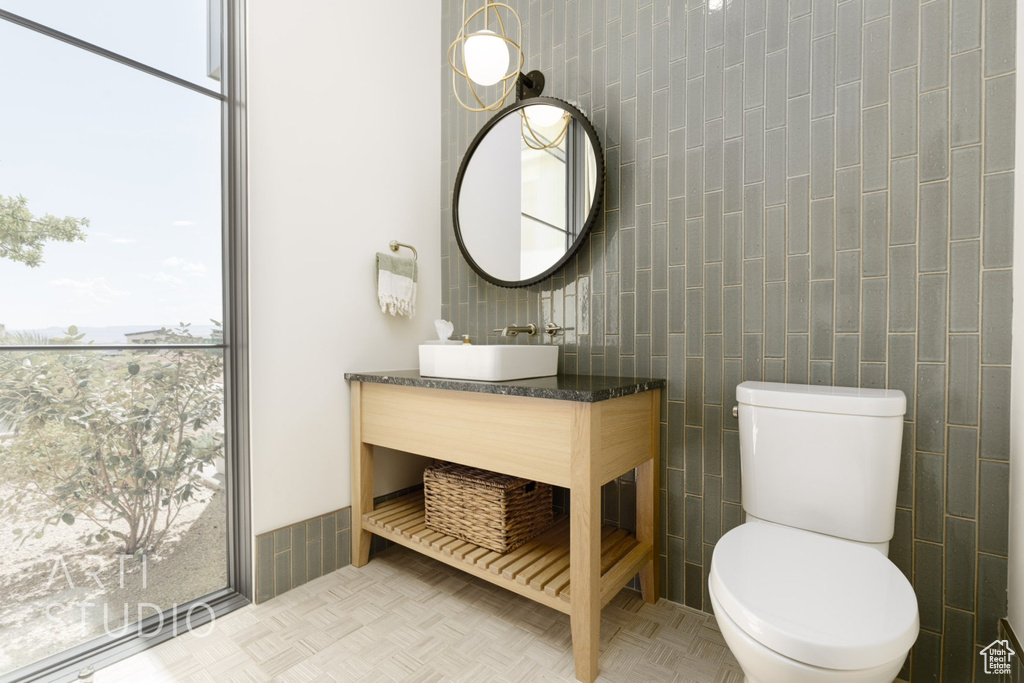 Bathroom with vanity, toilet, and tile walls