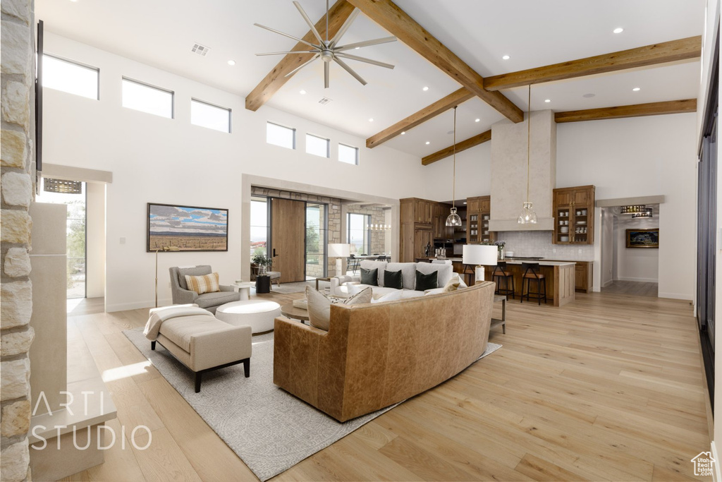 Living room featuring ceiling fan, light hardwood / wood-style flooring, a wealth of natural light, and a towering ceiling