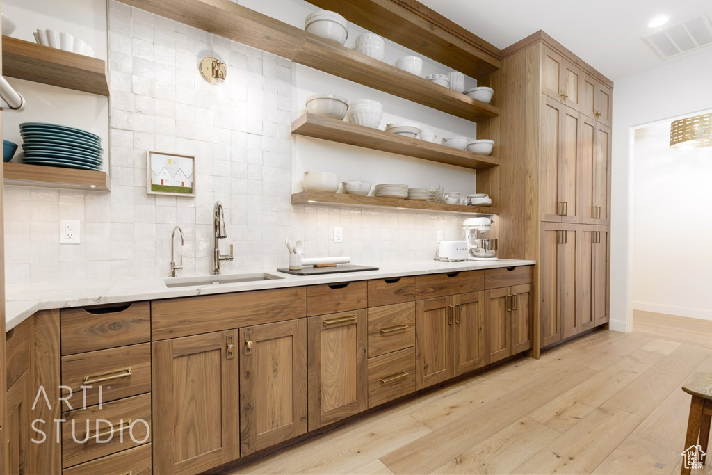 Kitchen featuring decorative backsplash, sink, and light wood-type flooring