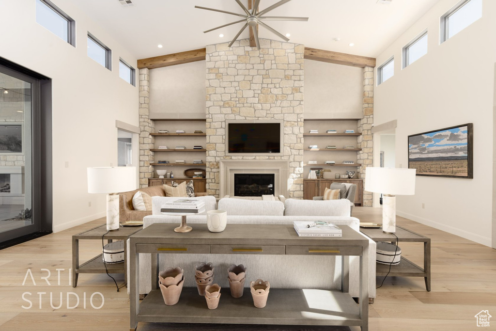 Living room with light hardwood / wood-style flooring, a stone fireplace, beam ceiling, high vaulted ceiling, and ceiling fan