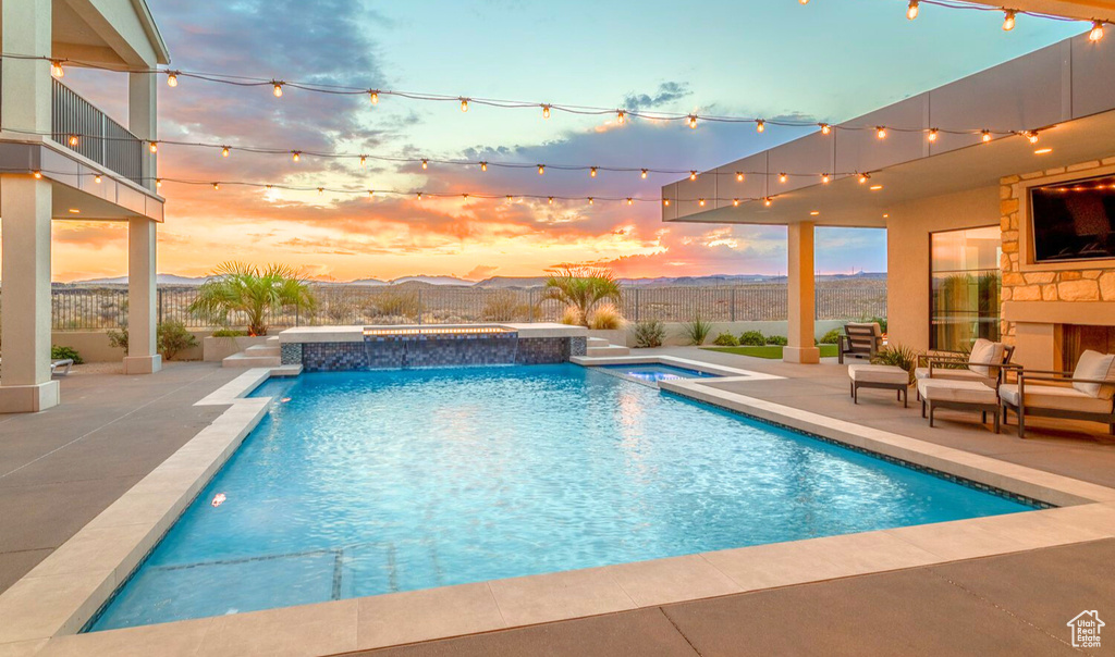 Pool at dusk with an in ground hot tub and a patio area