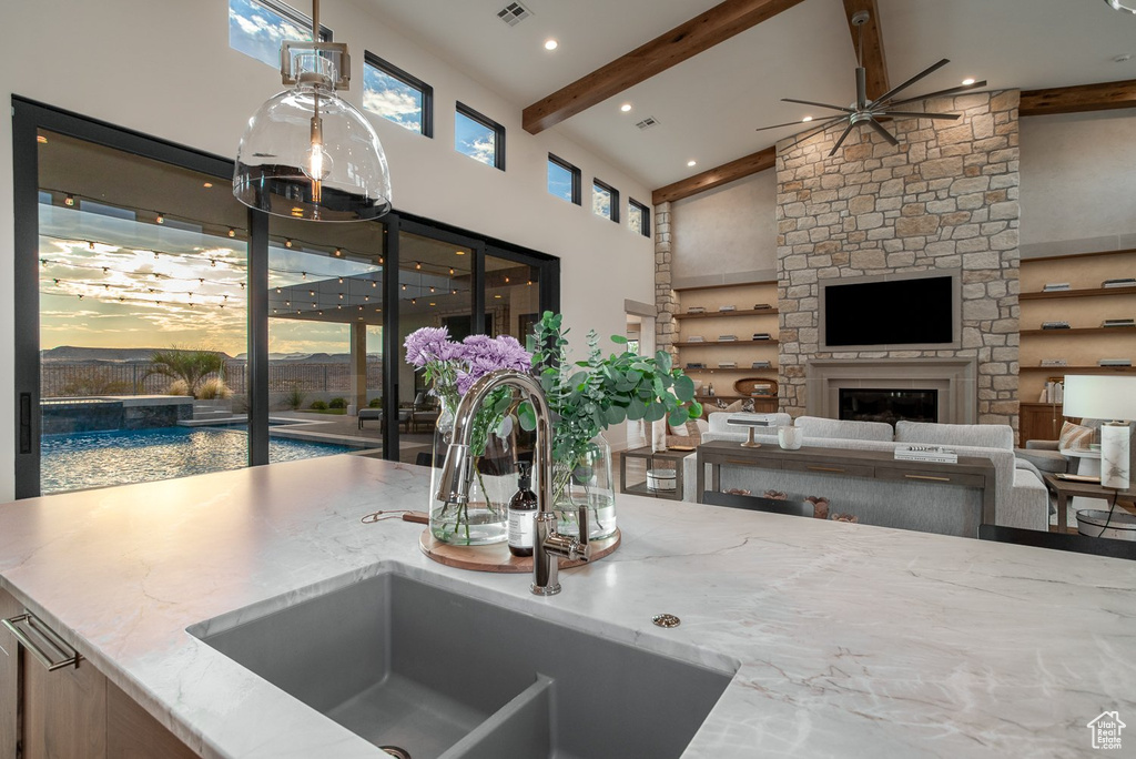 Kitchen featuring decorative light fixtures, a fireplace, ceiling fan, high vaulted ceiling, and beamed ceiling