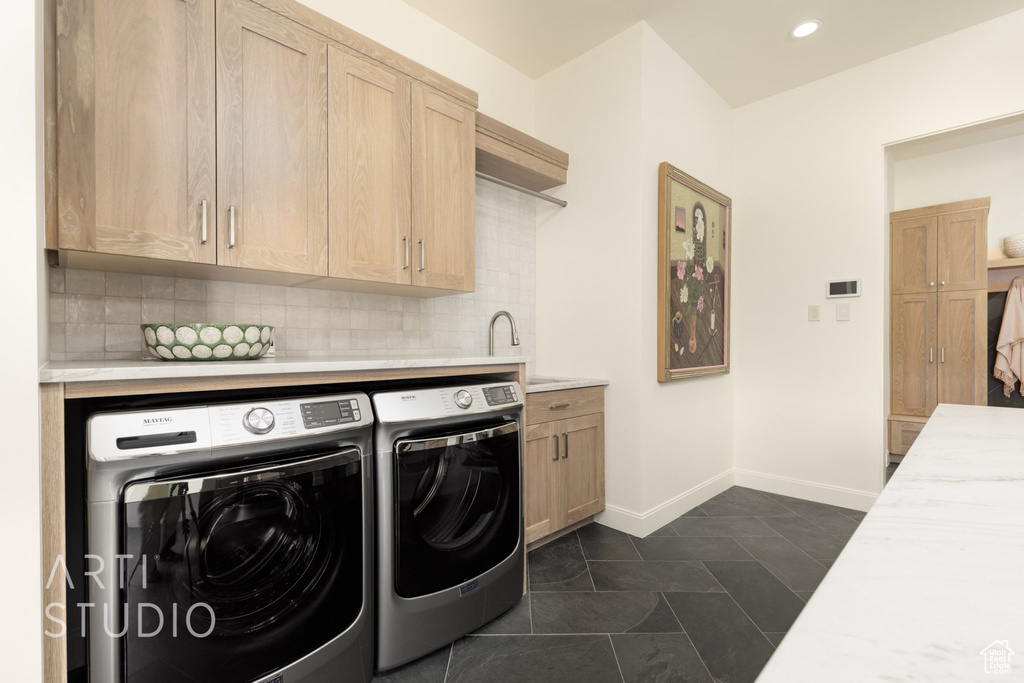 Clothes washing area with sink, cabinets, independent washer and dryer, and dark tile patterned flooring