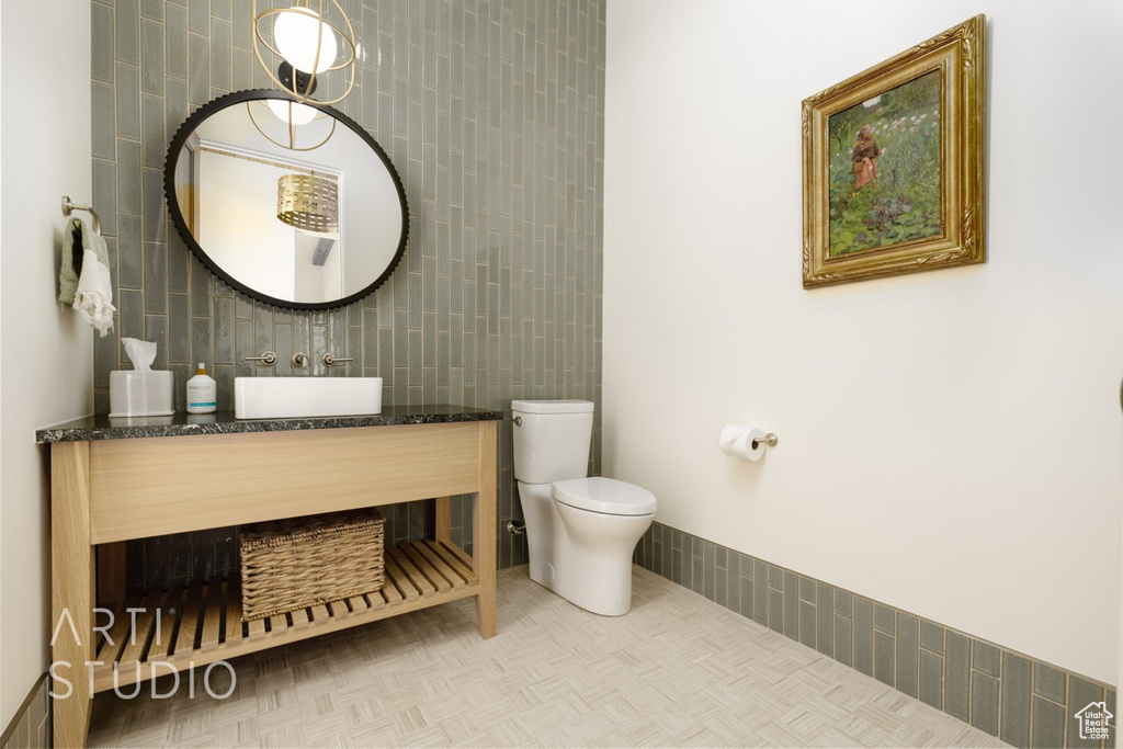 Bathroom featuring sink, tile walls, toilet, and tile patterned flooring