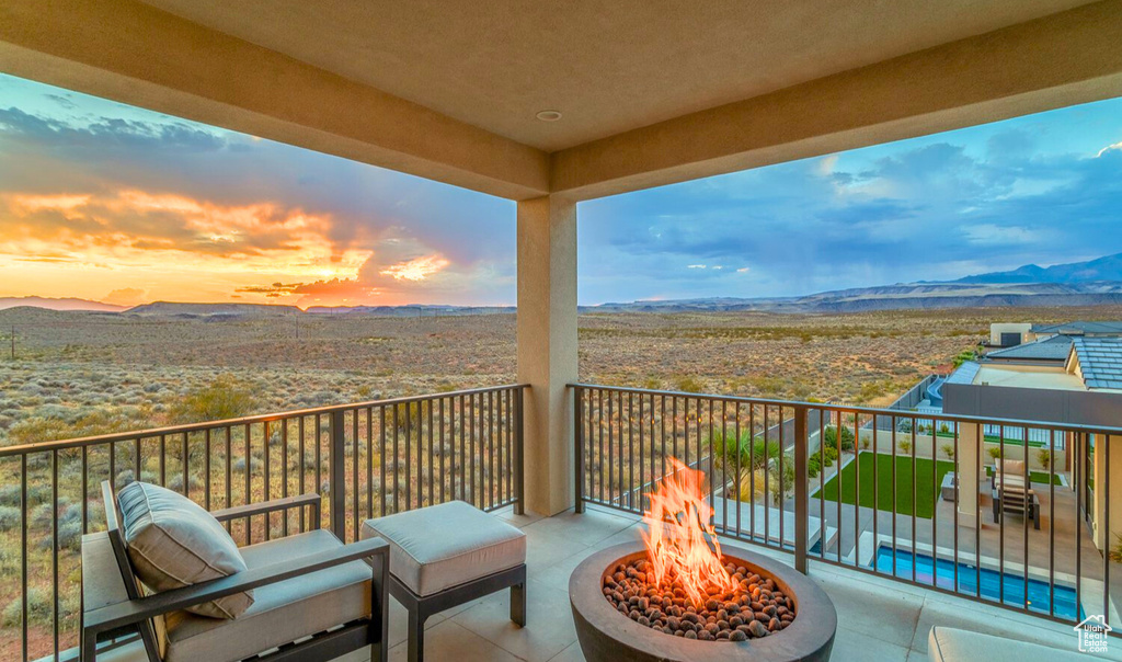 Balcony at dusk featuring a mountain view and a fire pit