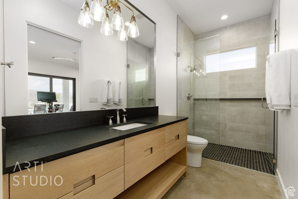 Bathroom with vanity, a shower with shower door, and toilet