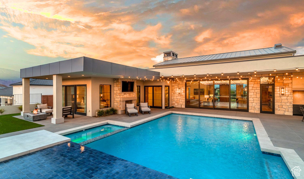 Pool at dusk with a patio and an outdoor hangout area