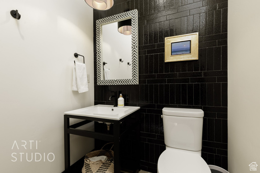 Bathroom featuring vanity, tile walls, and toilet