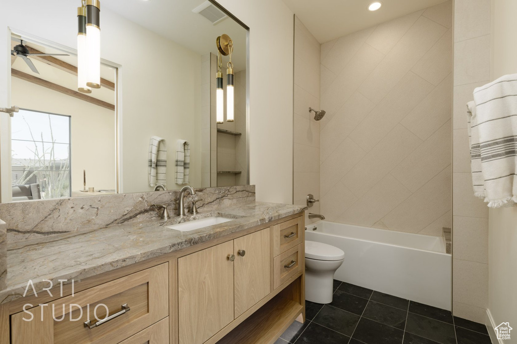 Full bathroom featuring tiled shower / bath, toilet, vanity, ceiling fan, and tile patterned floors