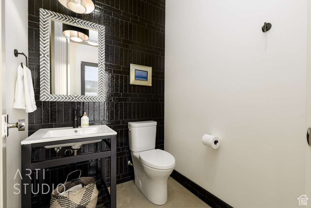 Bathroom with tasteful backsplash, sink, tile walls, tile patterned flooring, and toilet