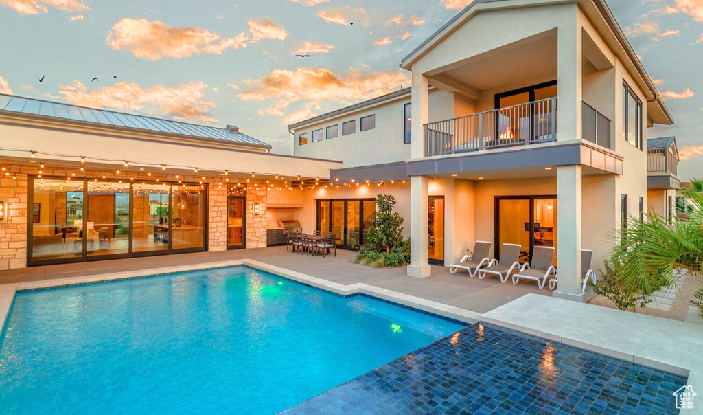 Pool at dusk featuring a patio