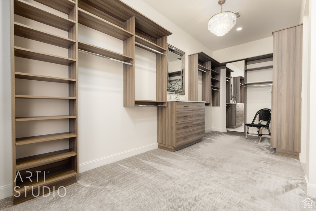 Spacious closet with a notable chandelier and light colored carpet