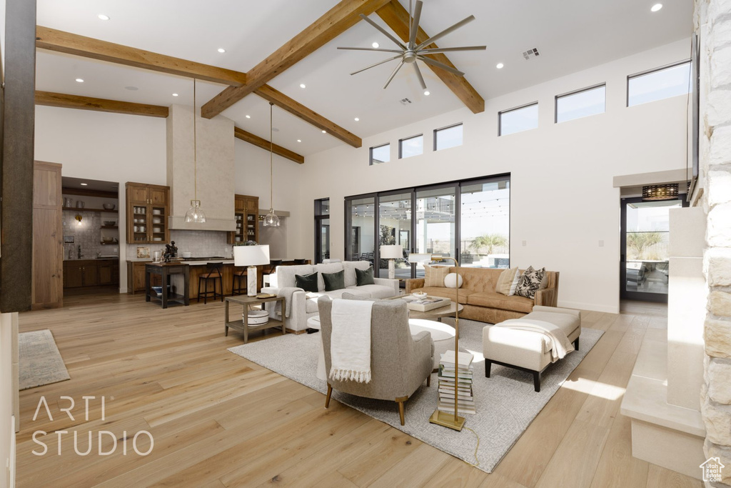 Living room with ceiling fan, beam ceiling, light wood-type flooring, and a high ceiling