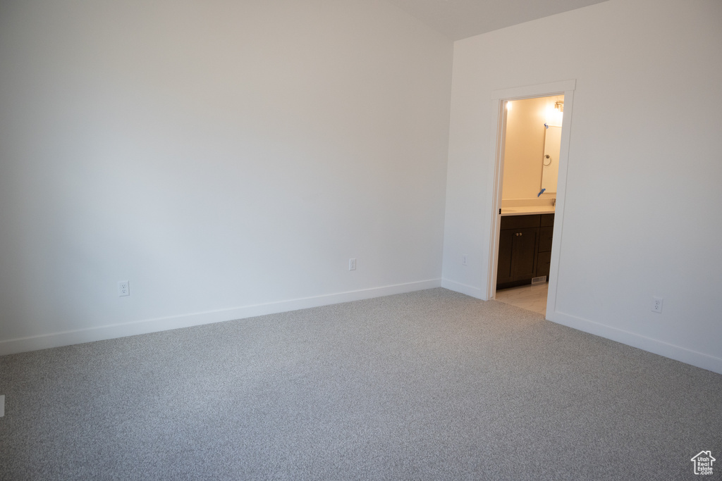 Unfurnished bedroom with ensuite bath and light carpet