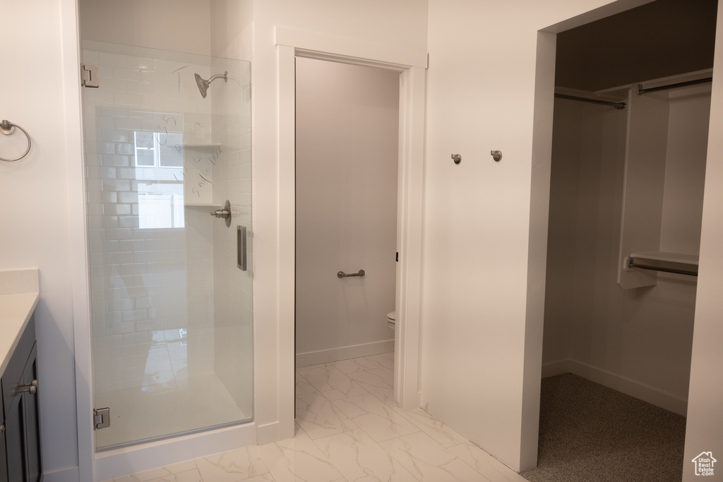 Bathroom with tile patterned floors, toilet, vanity, and a shower with shower door