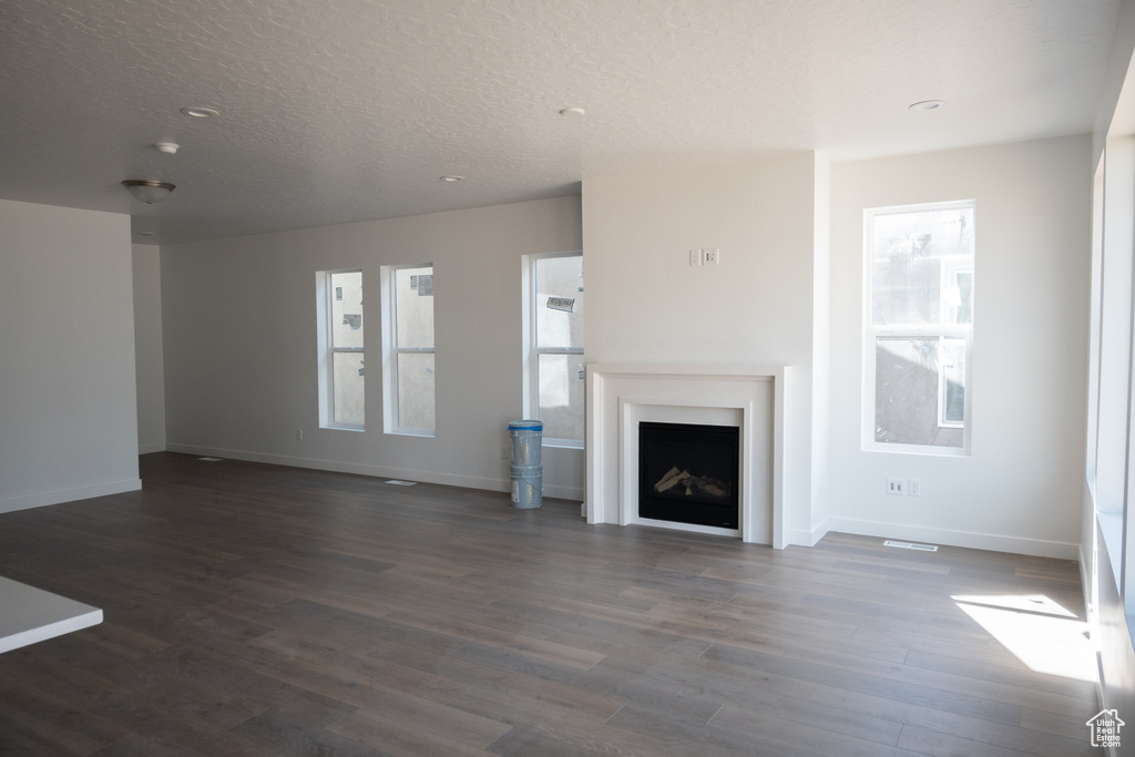 Unfurnished living room with hardwood / wood-style flooring and a textured ceiling