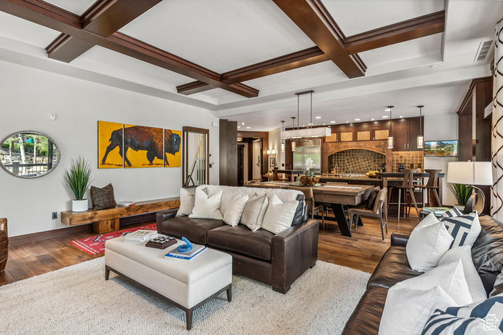 Living room featuring a fireplace, beam ceiling, hardwood / wood-style floors, and coffered ceiling