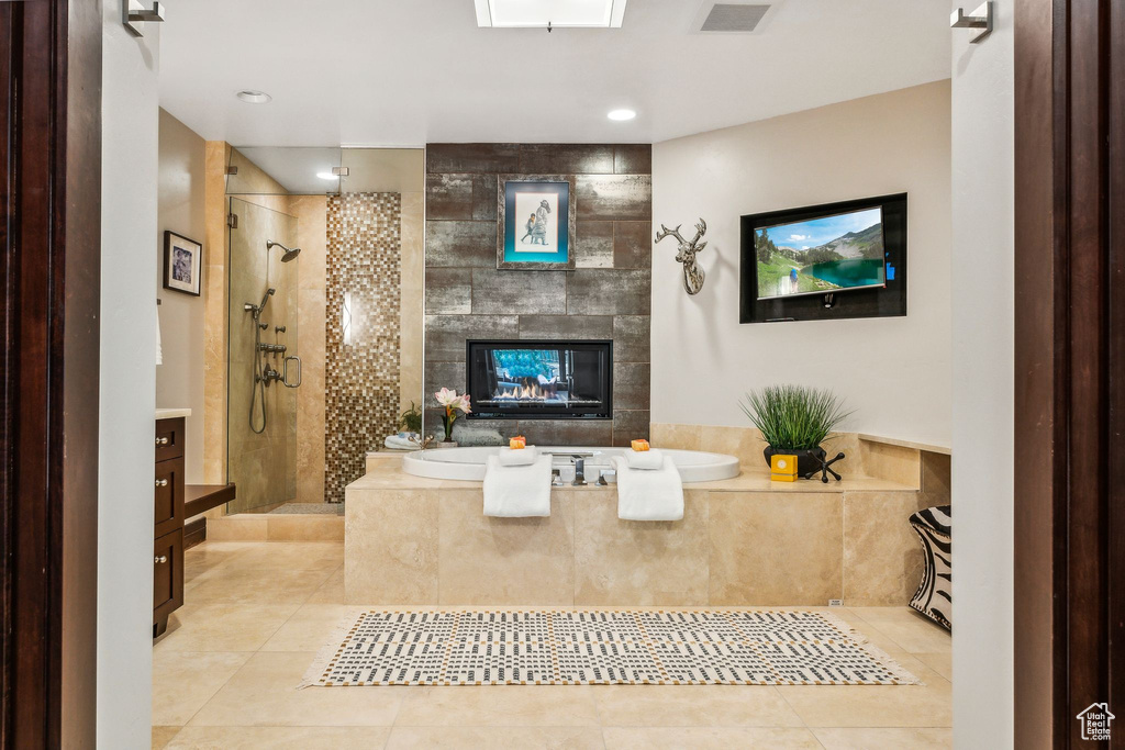 Bathroom with vanity, separate shower and tub, a fireplace, and tile patterned flooring