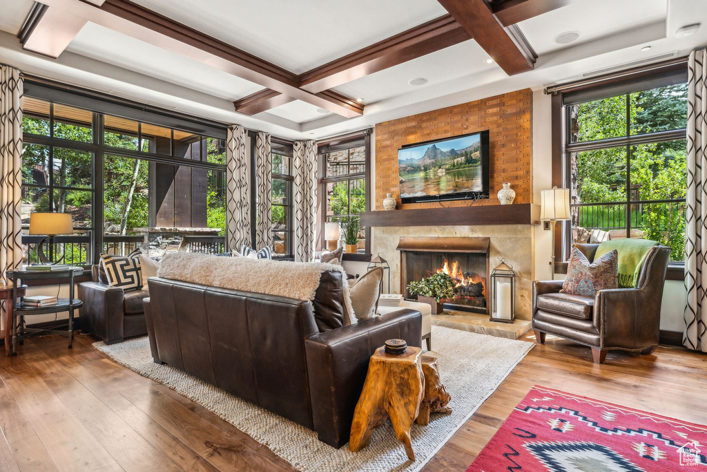 Living room featuring coffered ceiling, light wood-type flooring, and plenty of natural light