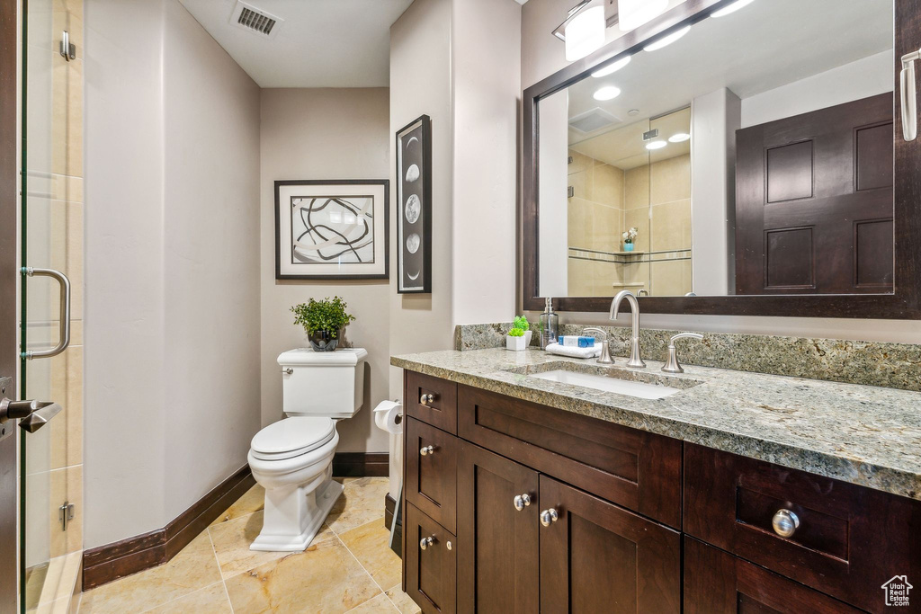 Bathroom featuring tile patterned floors, vanity, walk in shower, and toilet